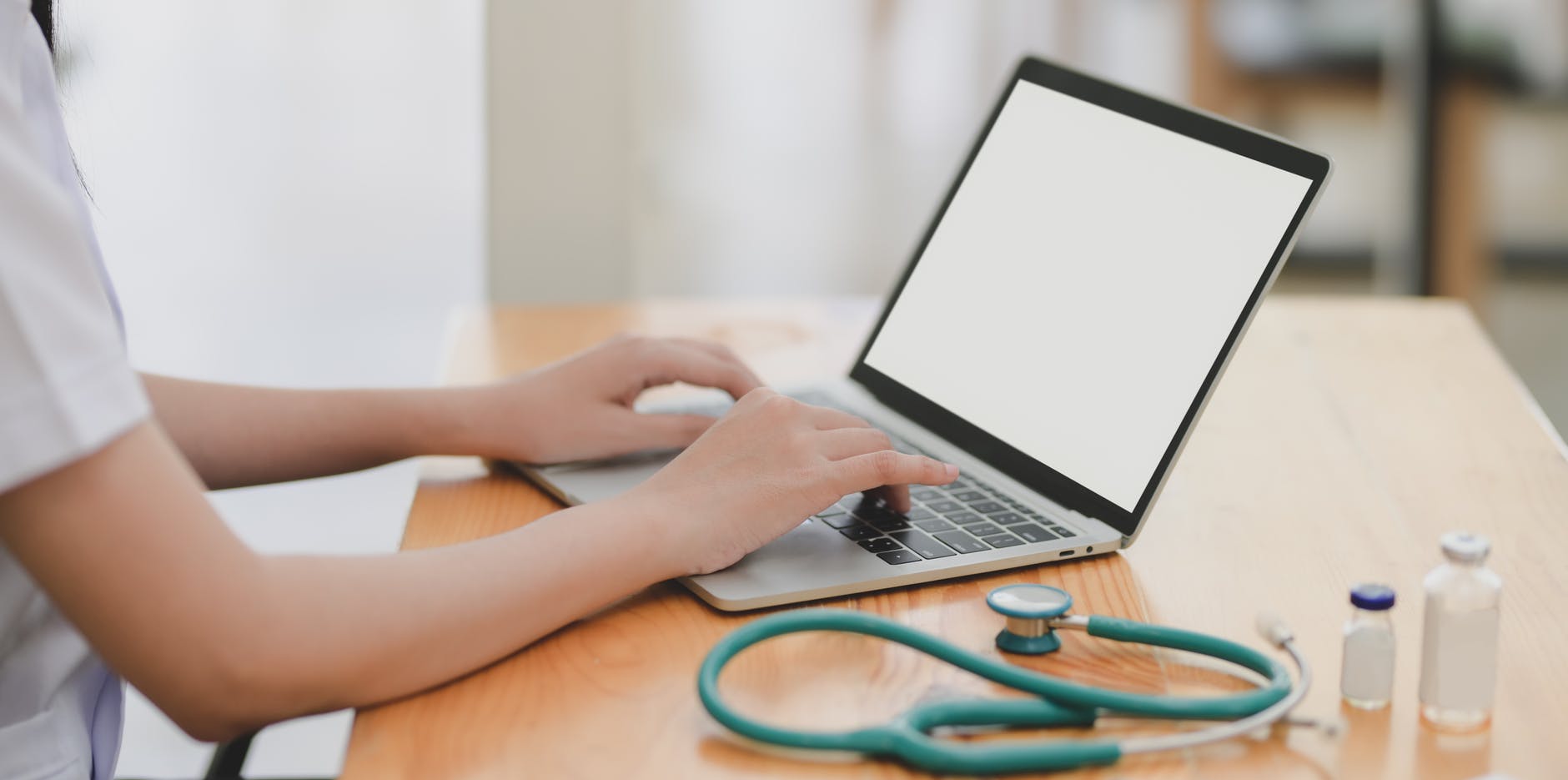 laptop near teal stethoscope in wooden table